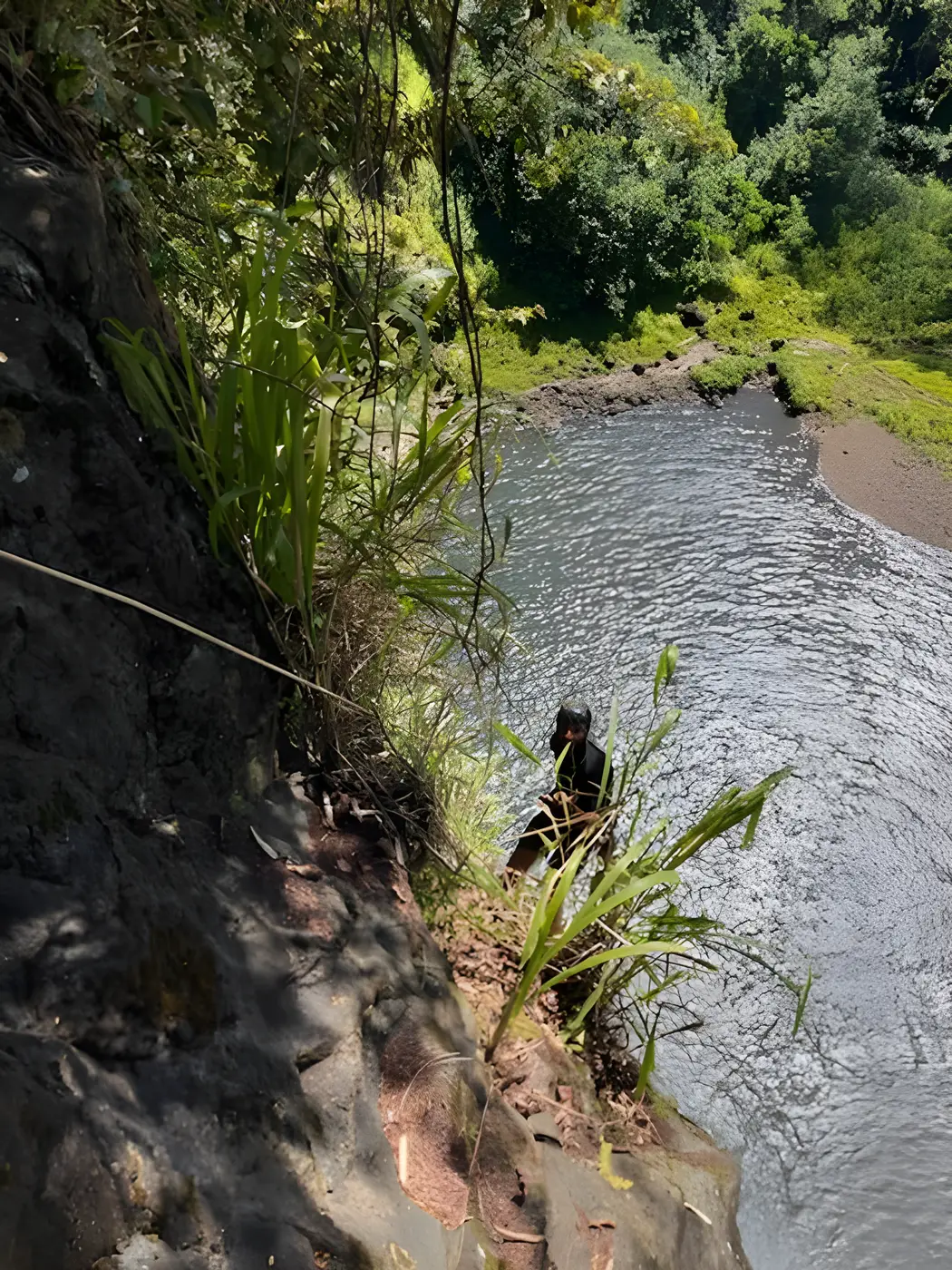 Looking down from the top of a cliff into a jungle pool
