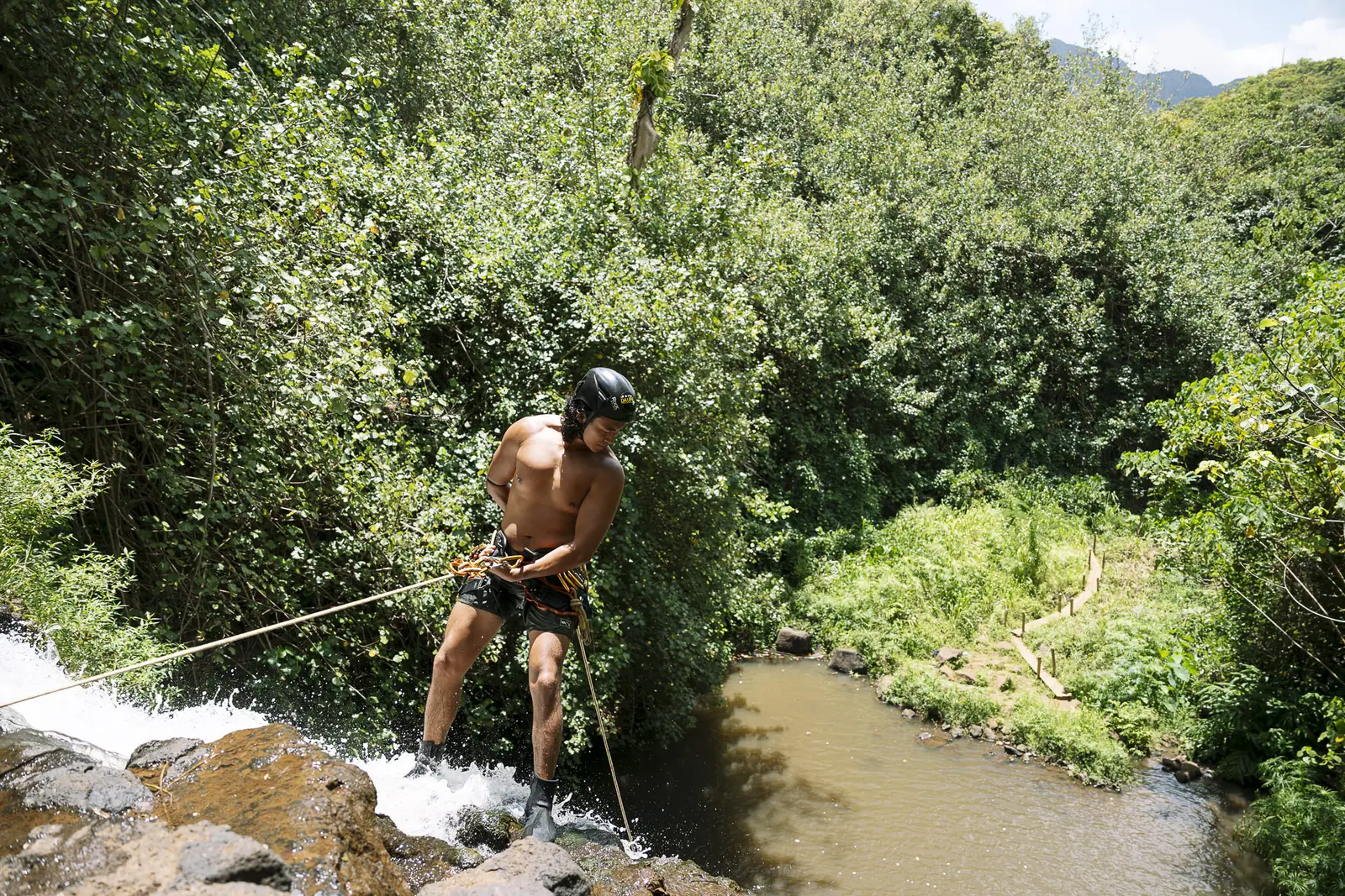 Starting a rappel at the top of a waterfall above the valley