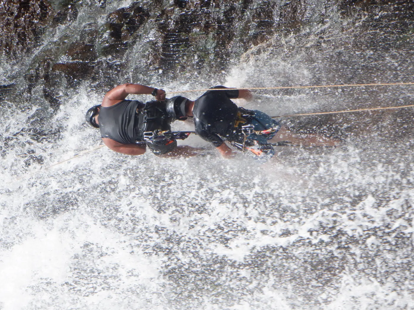 Tandem rappel through a large waterfall