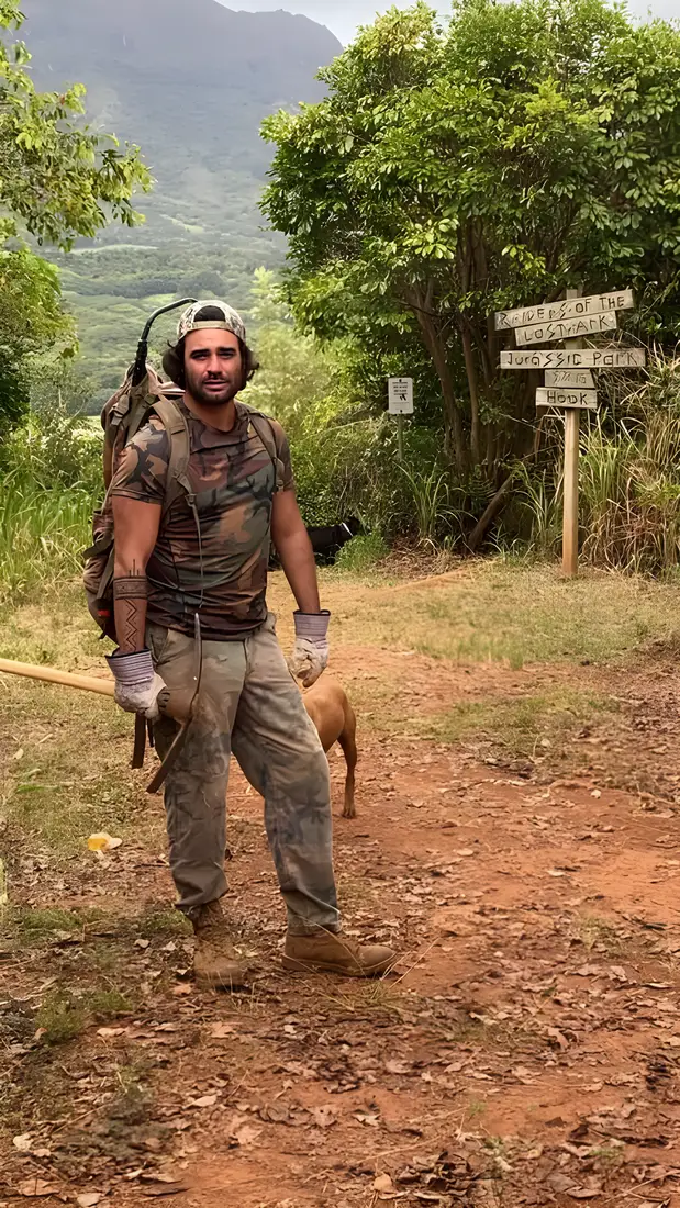 Renan with pack, gloves and dog at a trail signpost